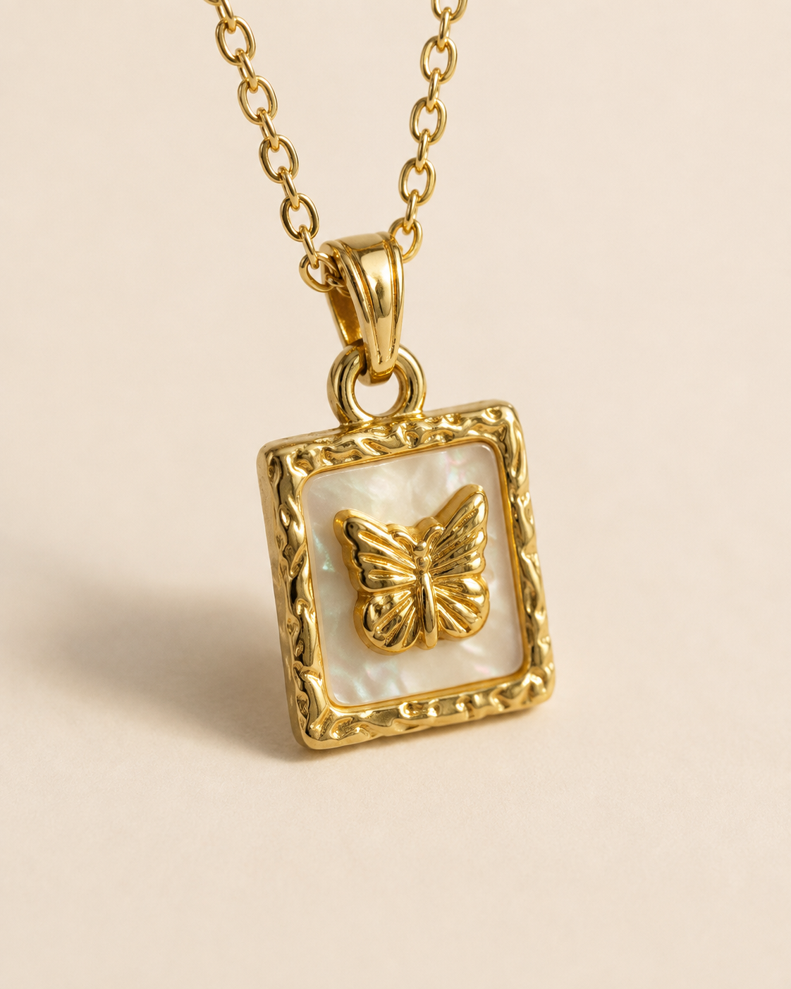 Close view of the raised butterfly relief, pale reflective rectangular field, and textured warm yellow-gold-toned frame.