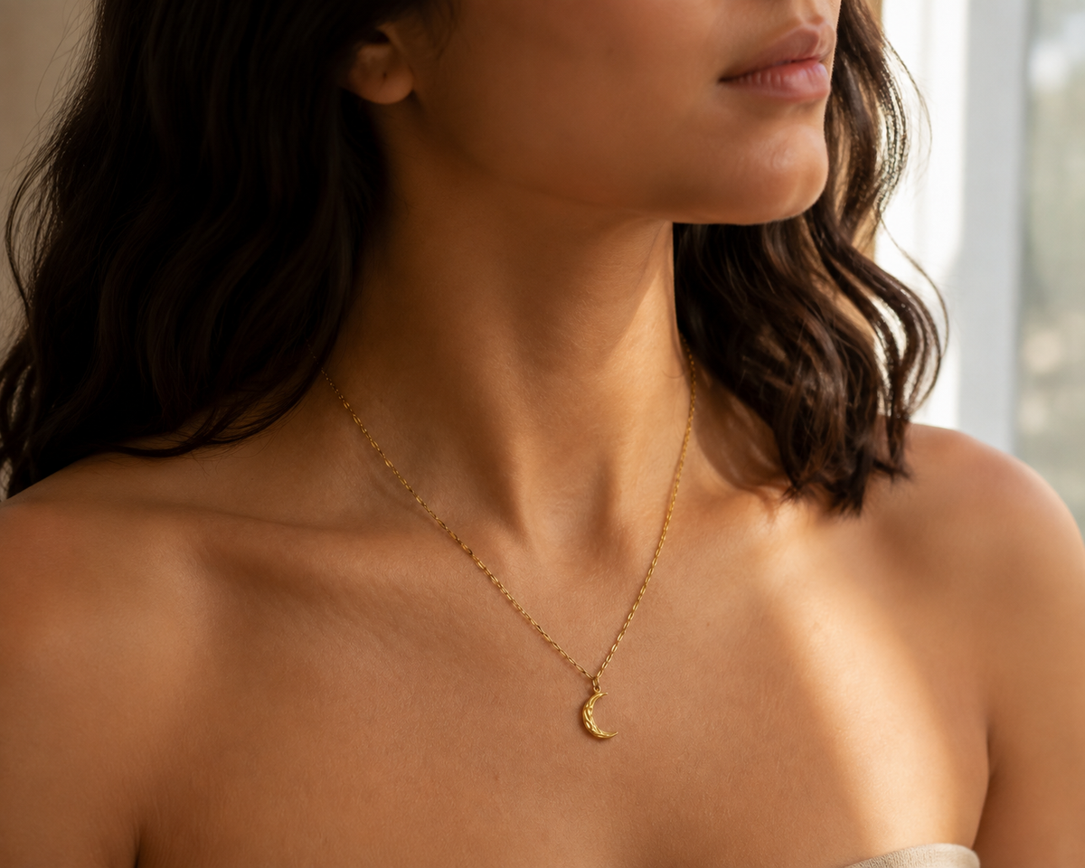 Second editorial view of the warm gold-toned asymmetrical crescent pendant necklace