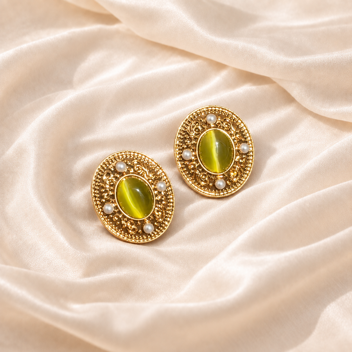 Pair of Viridian Court Earrings with olive-green oval centers and pale accents on cream silk