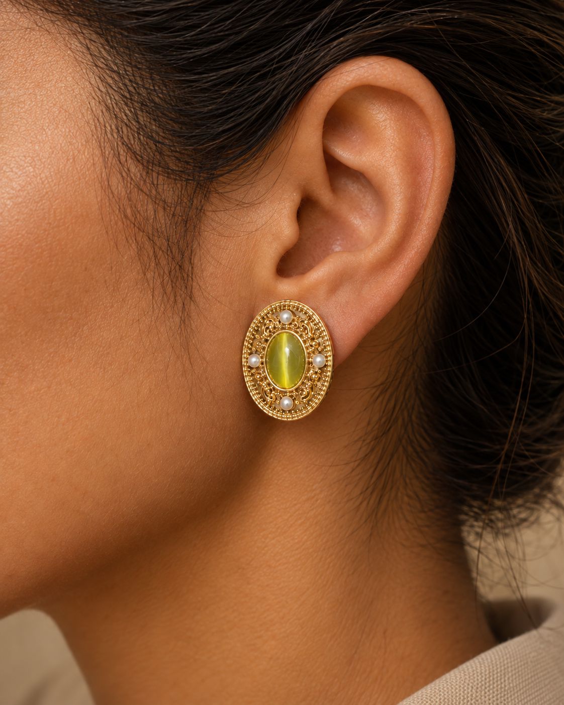 Close ear view wearing an ornate oval green earring
