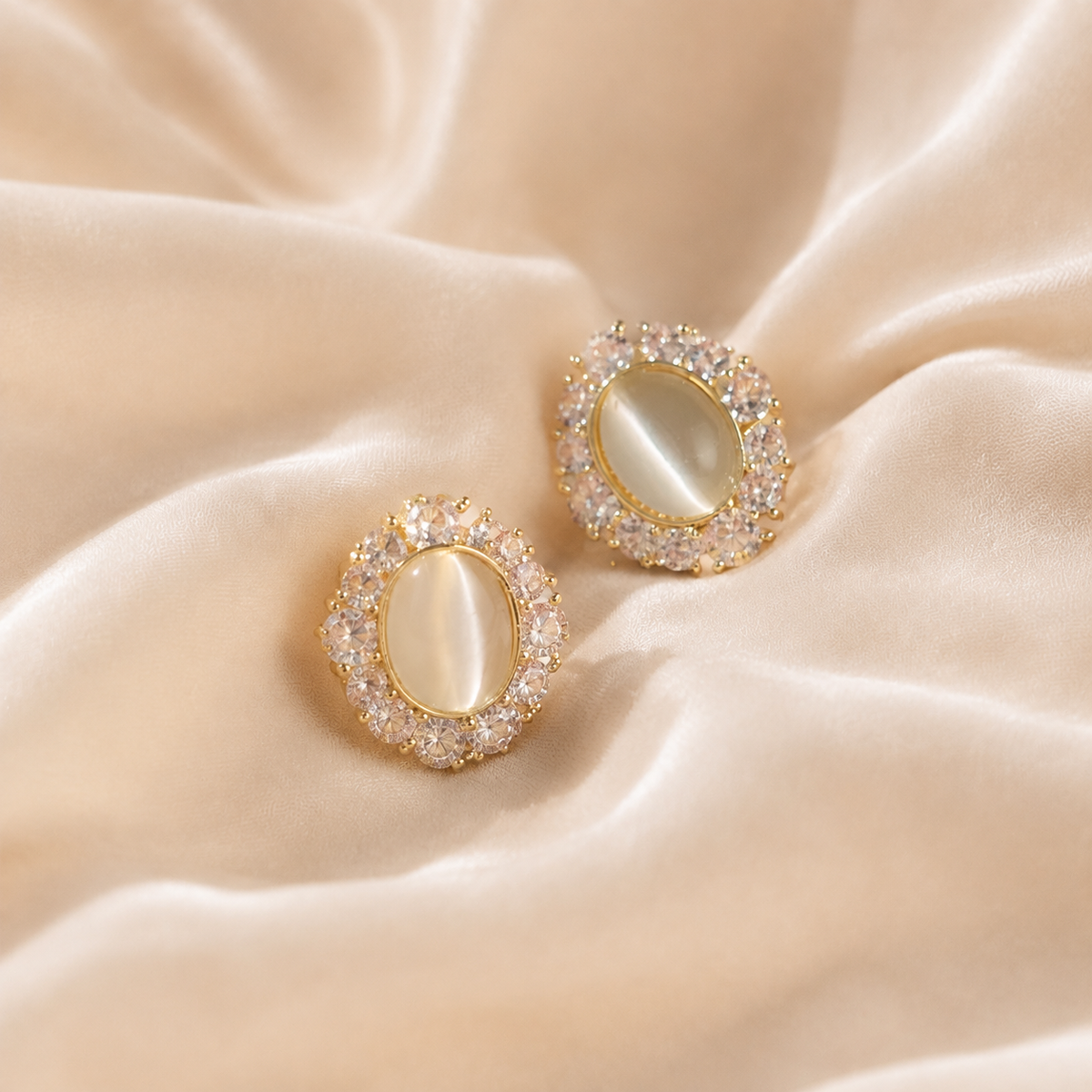 Celestial Keep Earrings, a matched pair with pale oval centers and halo-like details on warm cream silk