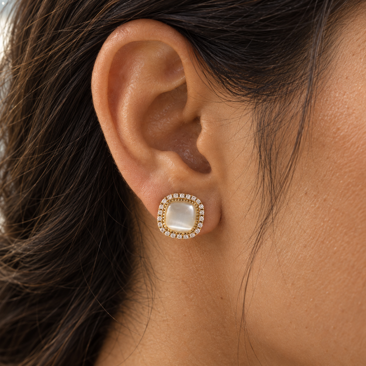 Close ear view wearing a pale rounded-square halo stud earring