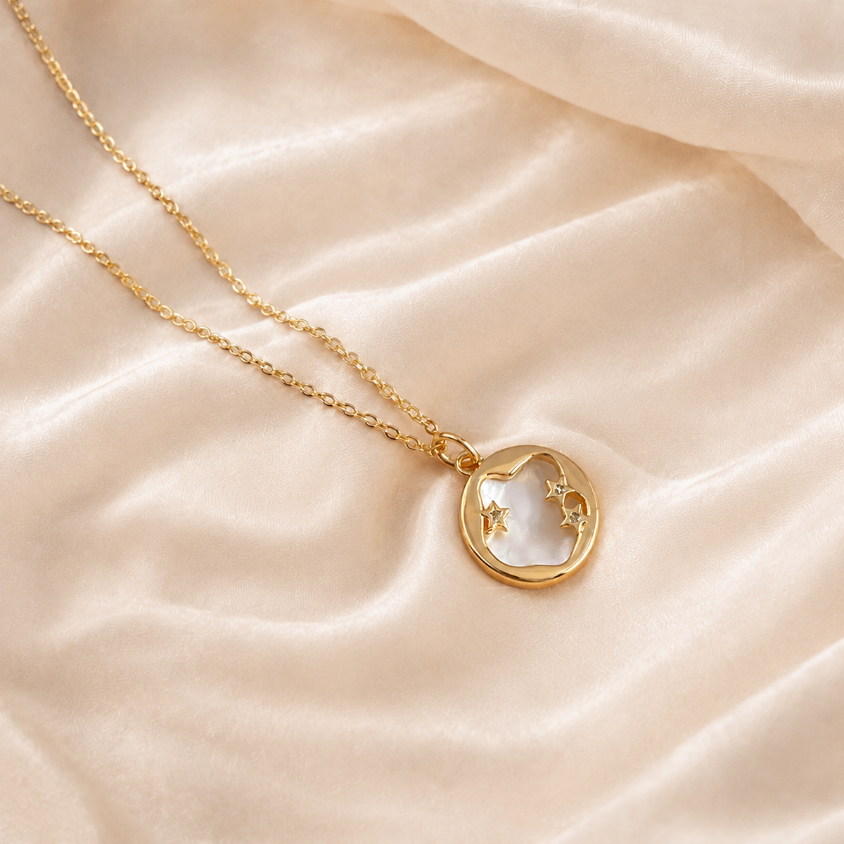 Aster Crest pendant necklace with a round pale pearlescent center, gold-tone frame, crescent-like arc, and three stars