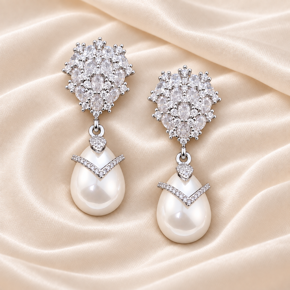 Matching clear-accent silver-tone drop earrings with white pear-shaped drops on light cream silk.