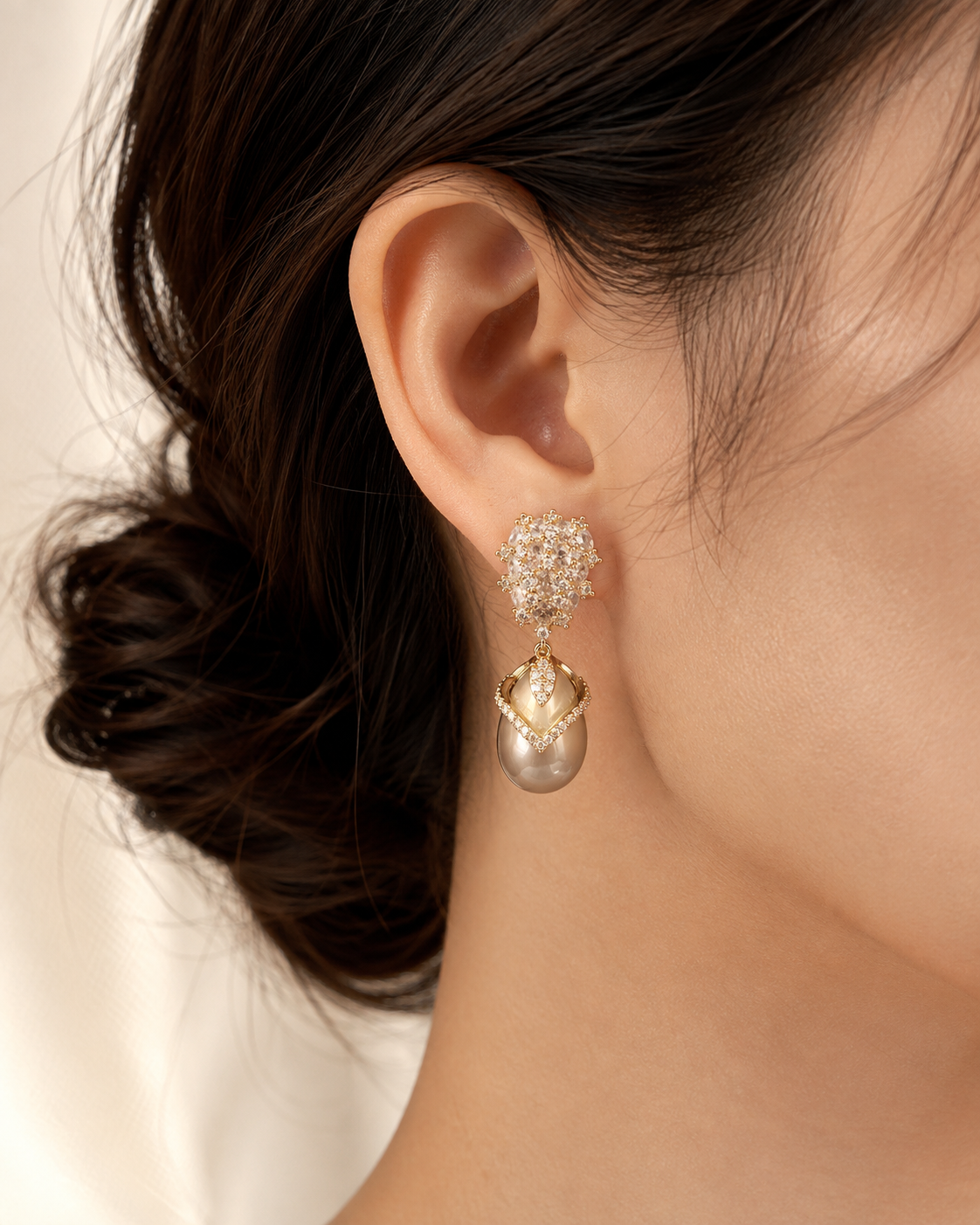 Close wearing view of a Misted Votive Earring with pale champagne zircon accents and a champagne-colored pearl drop.