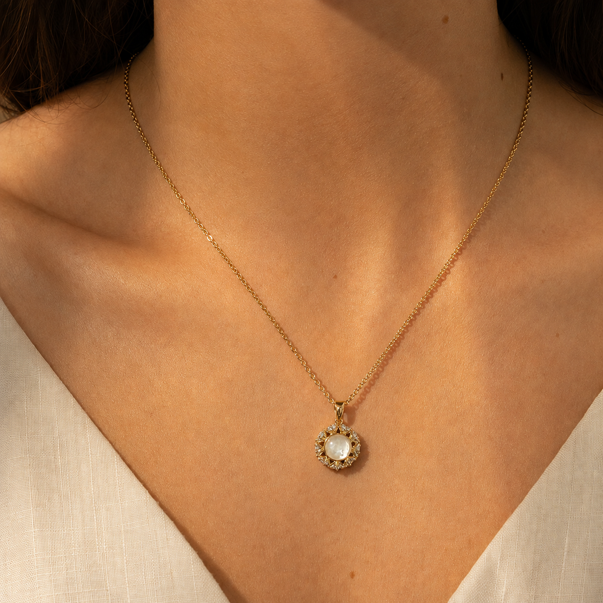 Close wearing view of the Aureole Inlay Pendant Necklace with a warm gold-toned chain and pale iridescent-looking halo pendant.