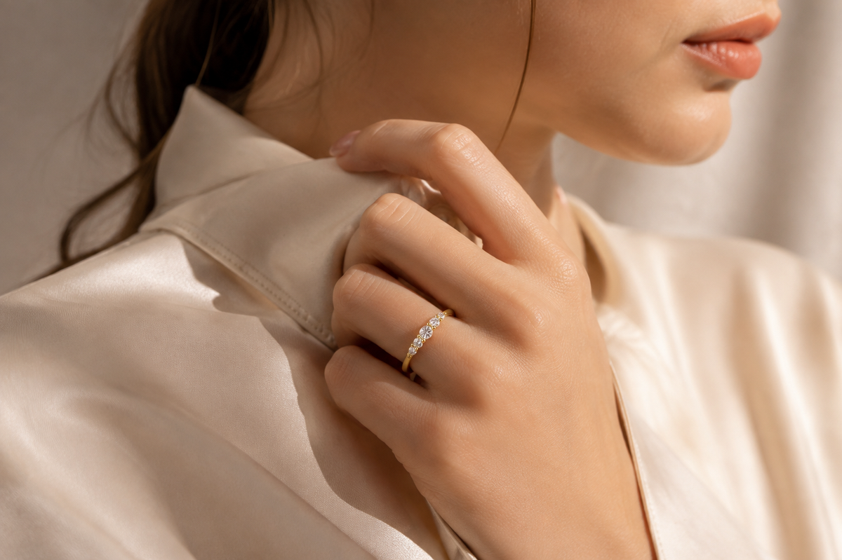 Editorial hand view of a slim closed ring with five graduated clear zircon accents