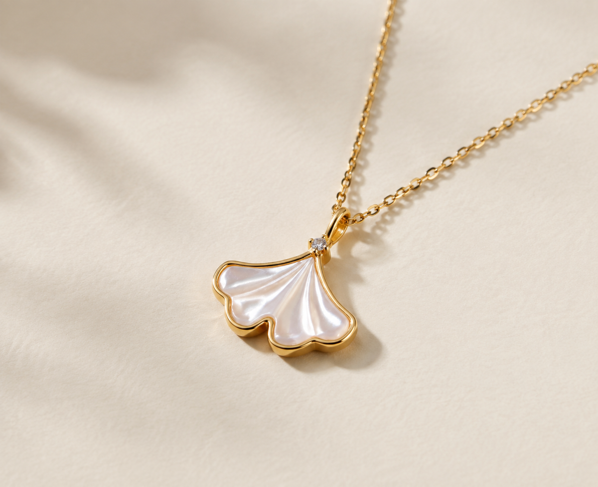 Close view of a fan-shaped shell leaf pendant with radiating lines and a small clear-looking accent