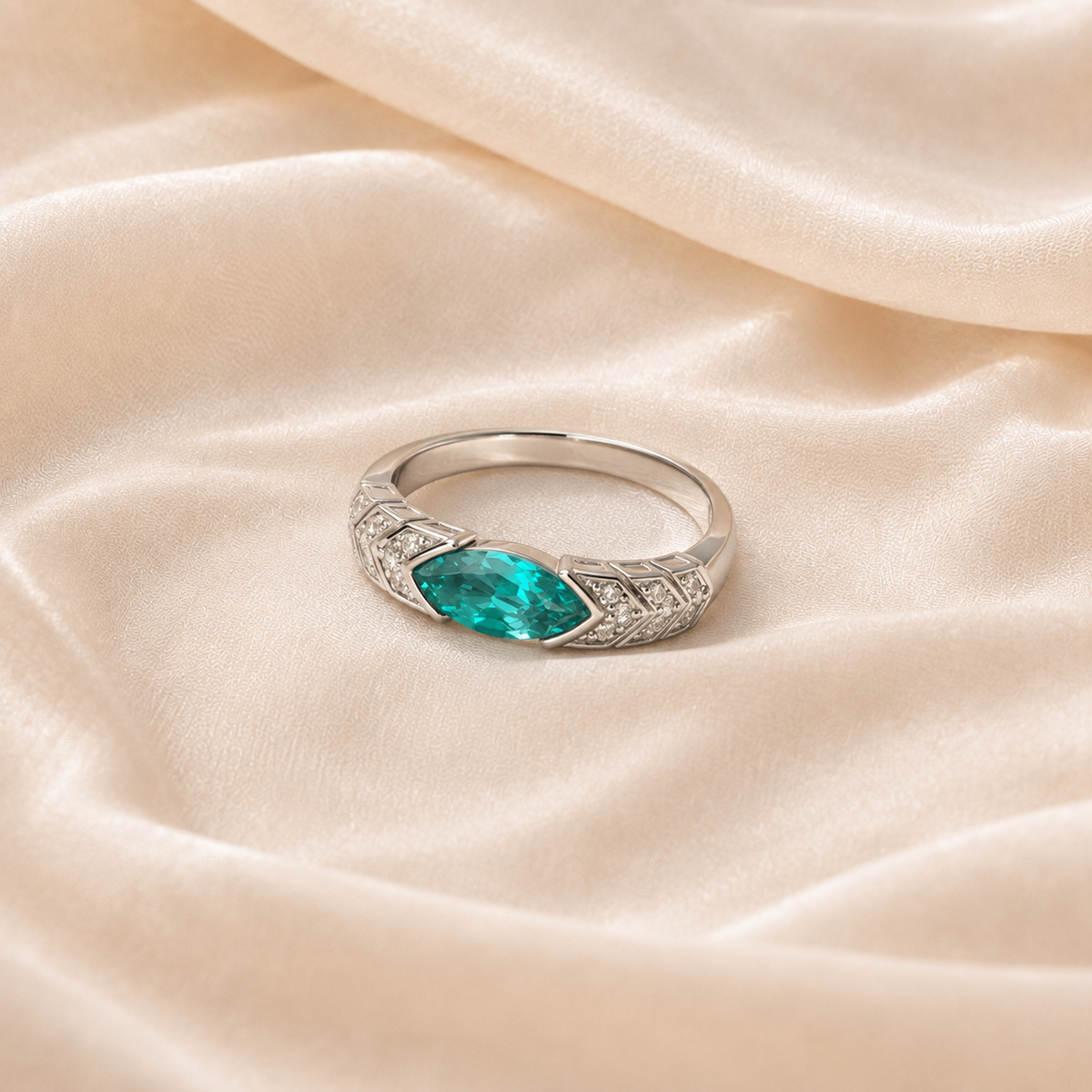 Lagoon Spire Ring with a vertical blue-green marquise-shaped center on cream silk