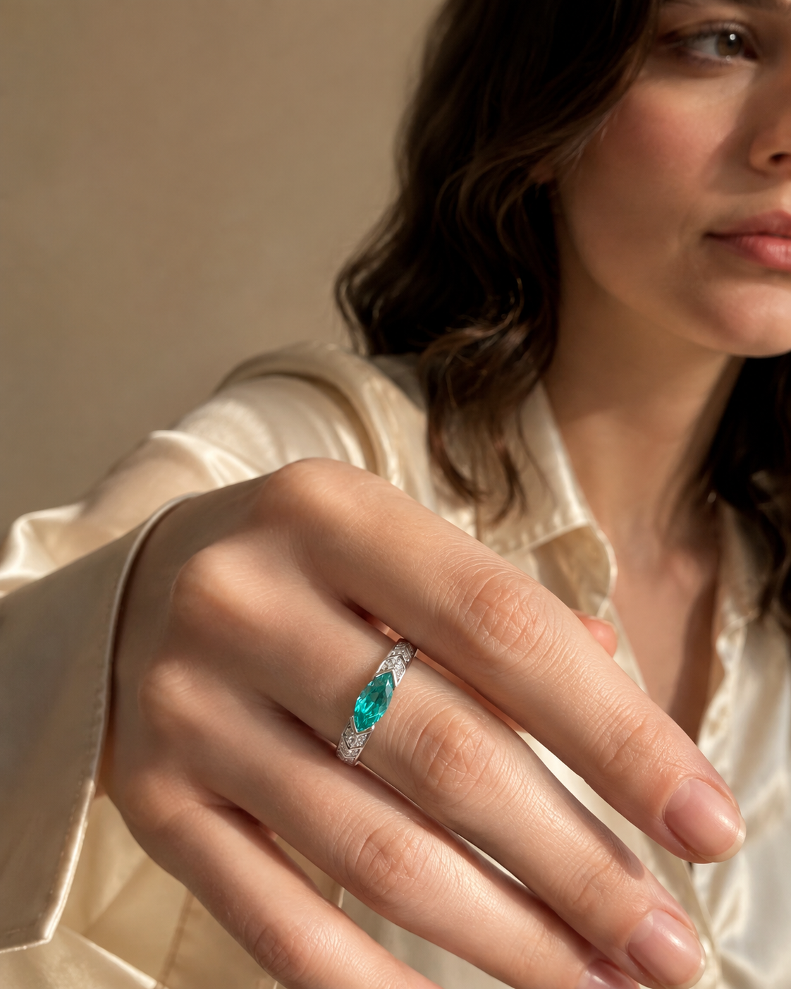 Editorial hand view of a narrow ring with a blue-green marquise-shaped center and stepped shoulders