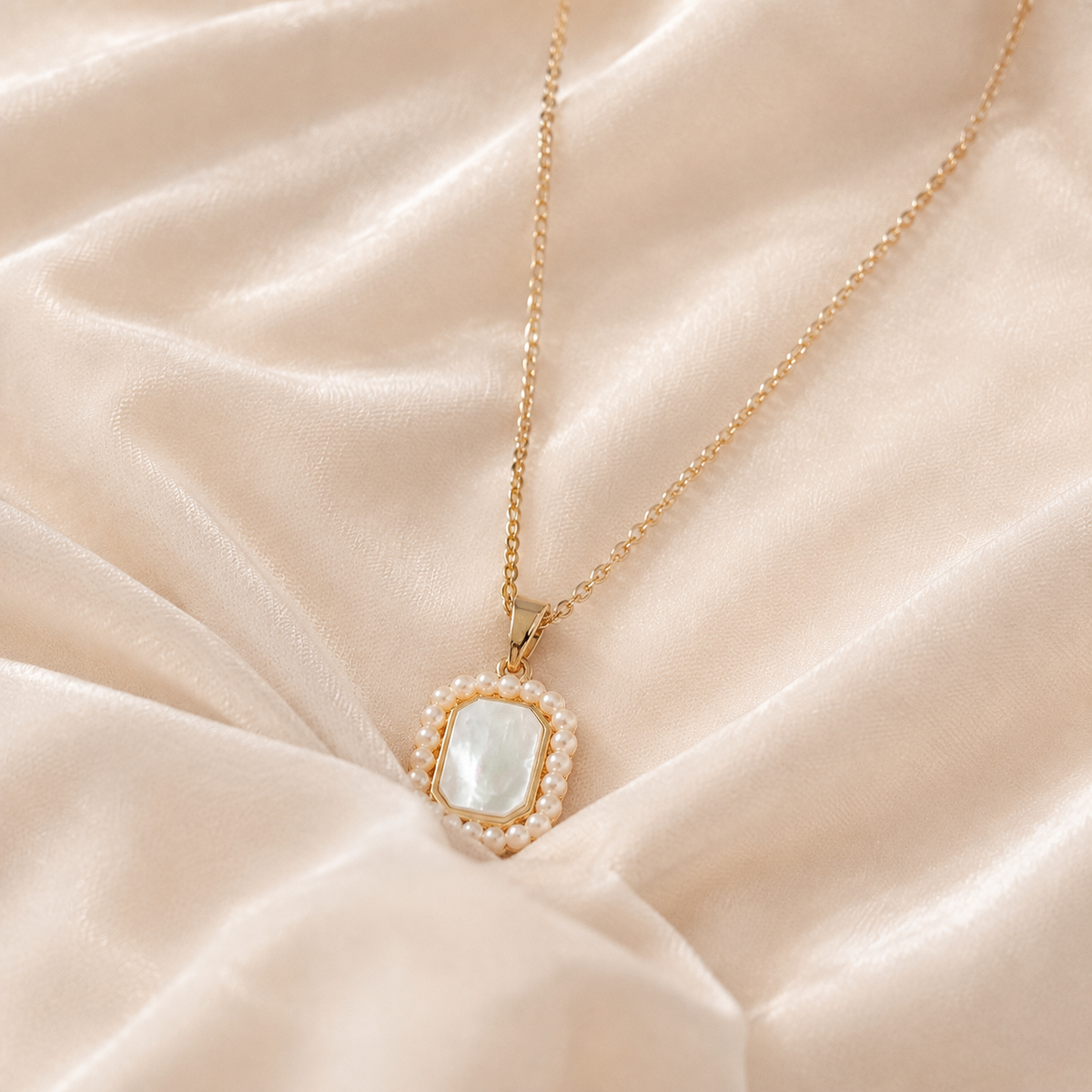 Folio Frame Pendant Necklace with a pale rectangular centre and white bead-like border on cream silk