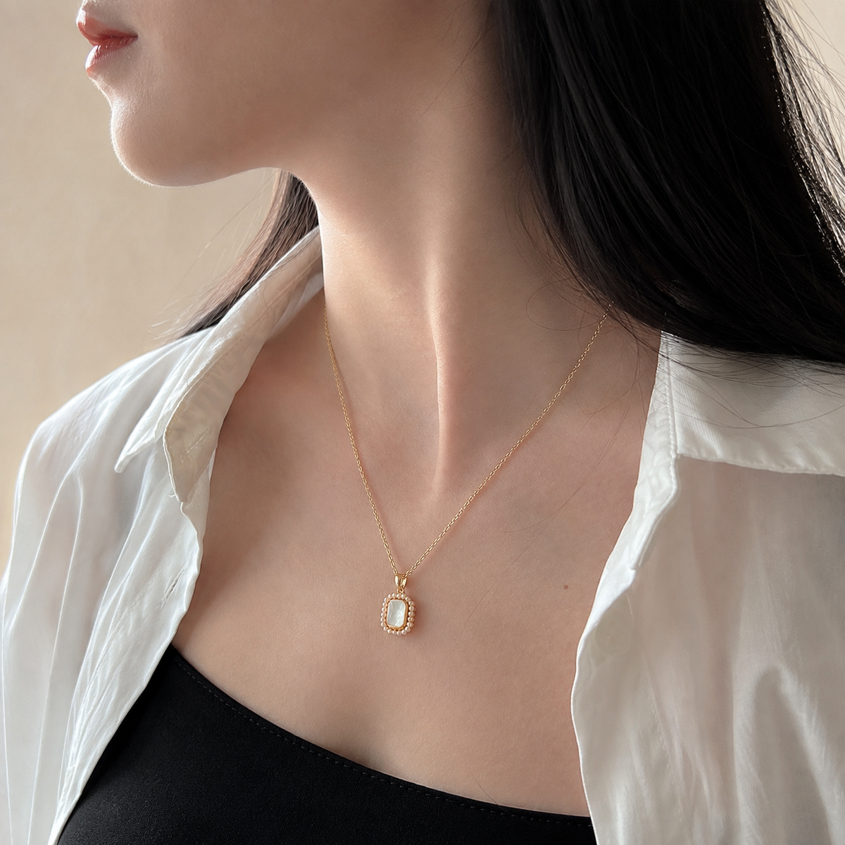 Side-profile upper-chest view of the Folio Frame Pendant Necklace worn with a white shirt