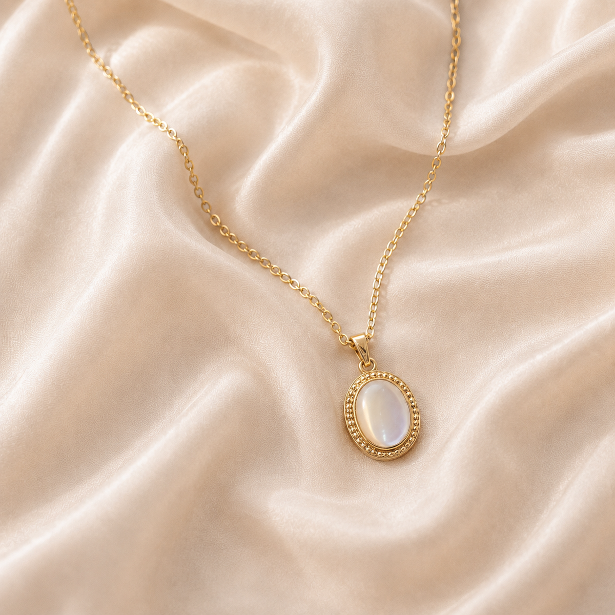 Gilt Memento Pendant Necklace with a pale iridescent oval centre on cream silk