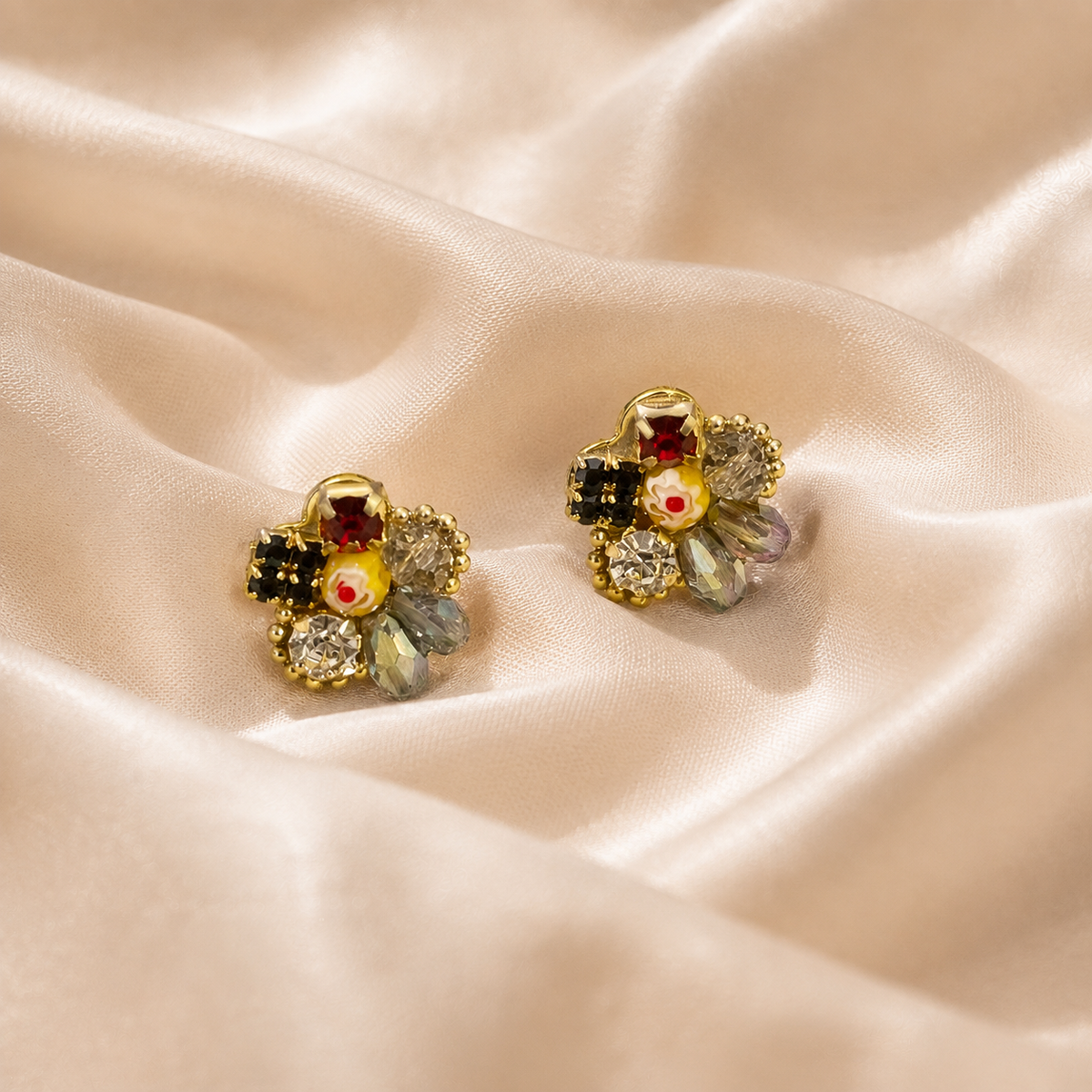 Coronet Blossom Earrings with a paired floral stud design and colored detailing on warm cream silk