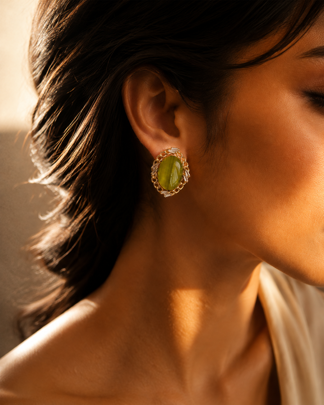 Green oval stud-front earring worn in a side-profile view