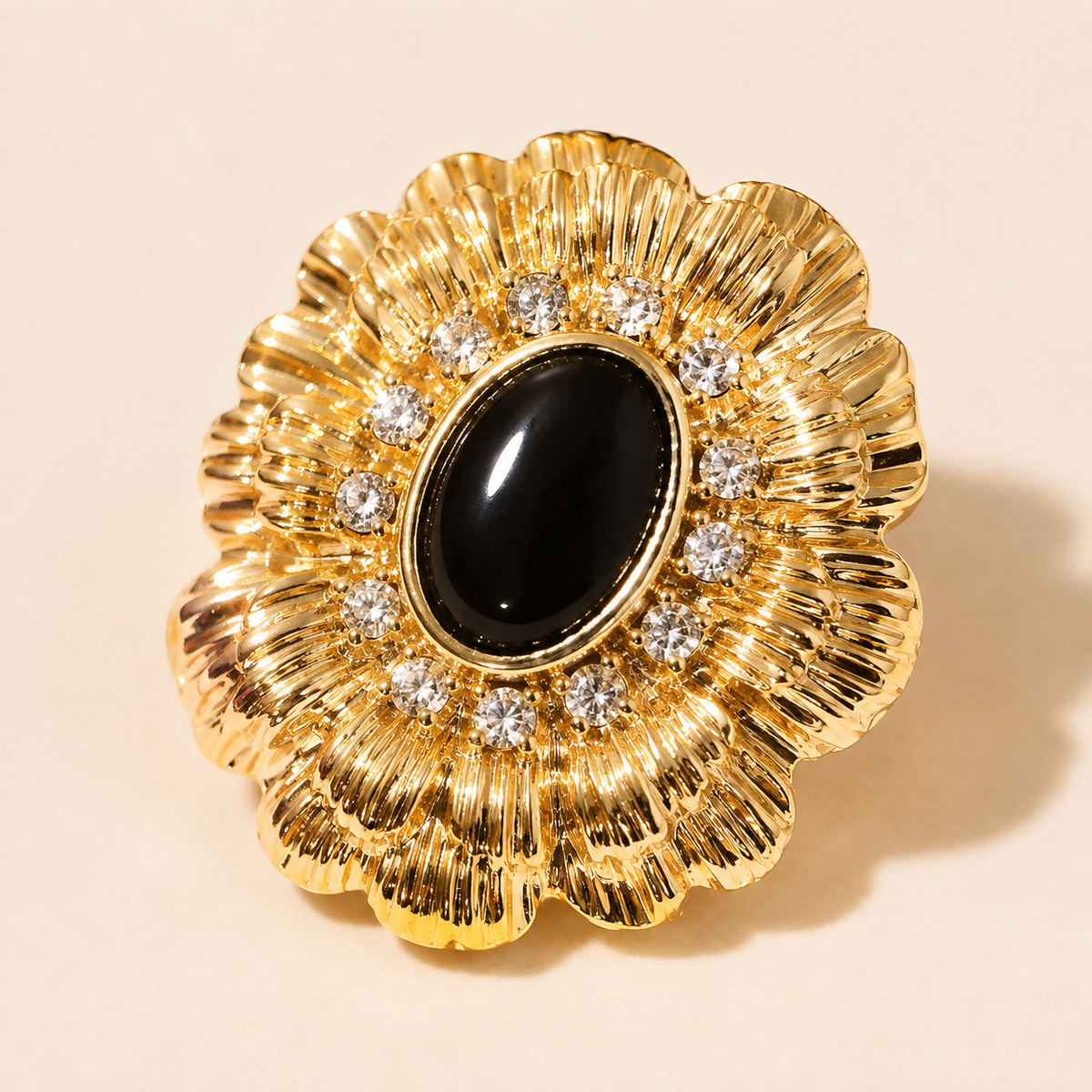 Close-up of a gold-tone ridged radiating earring with a dark oval center and clear round accents