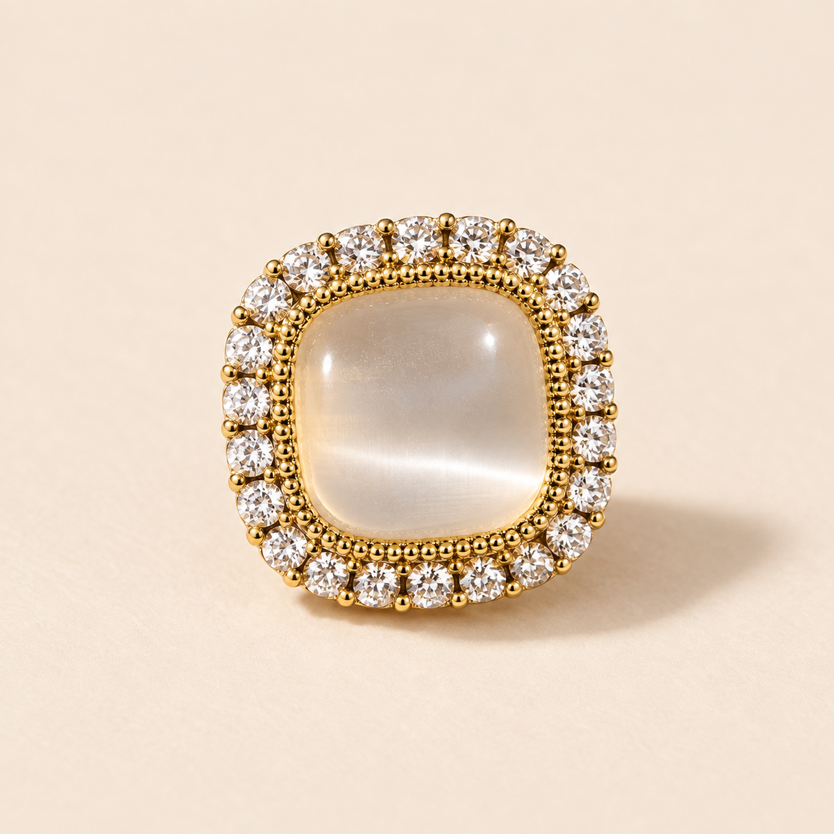 Close view of a pale rounded-square stud earring with a compact clear-looking halo