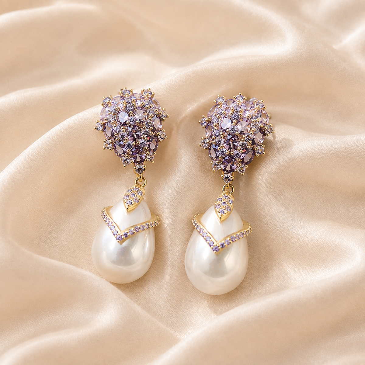 Matching violet faceted drop earrings with smooth white pear-shaped pearl drops arranged on pale cream silk.