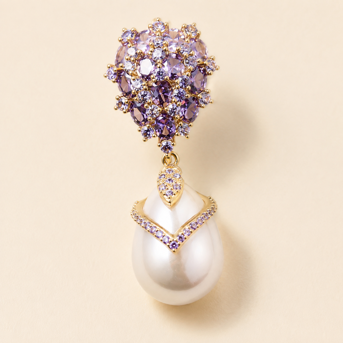 Close view of one violet faceted drop earring with a dense upper cluster, chevron frame, and smooth white pear-shaped pearl drop.